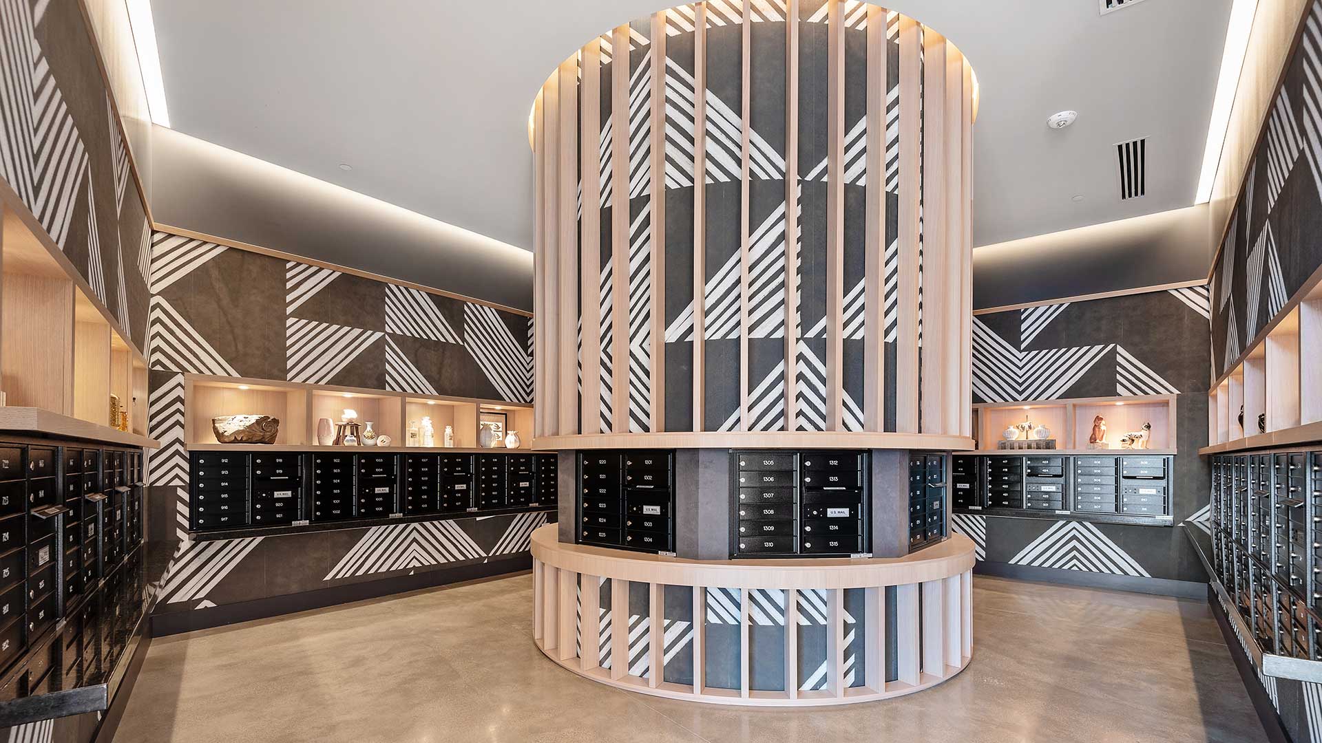 Eva resident mail room in Evanston with individual mailboxes, custom woodwork, geometric wall patterns, and built-in display shelving.