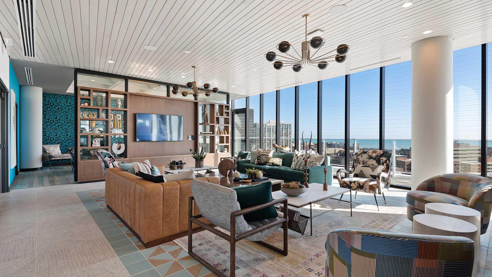 Eva Rooftop Sky Club lounge with sofas, armchairs, television, built-in shelving, and floor-to-ceiling windows overlooking Lake Michigan.