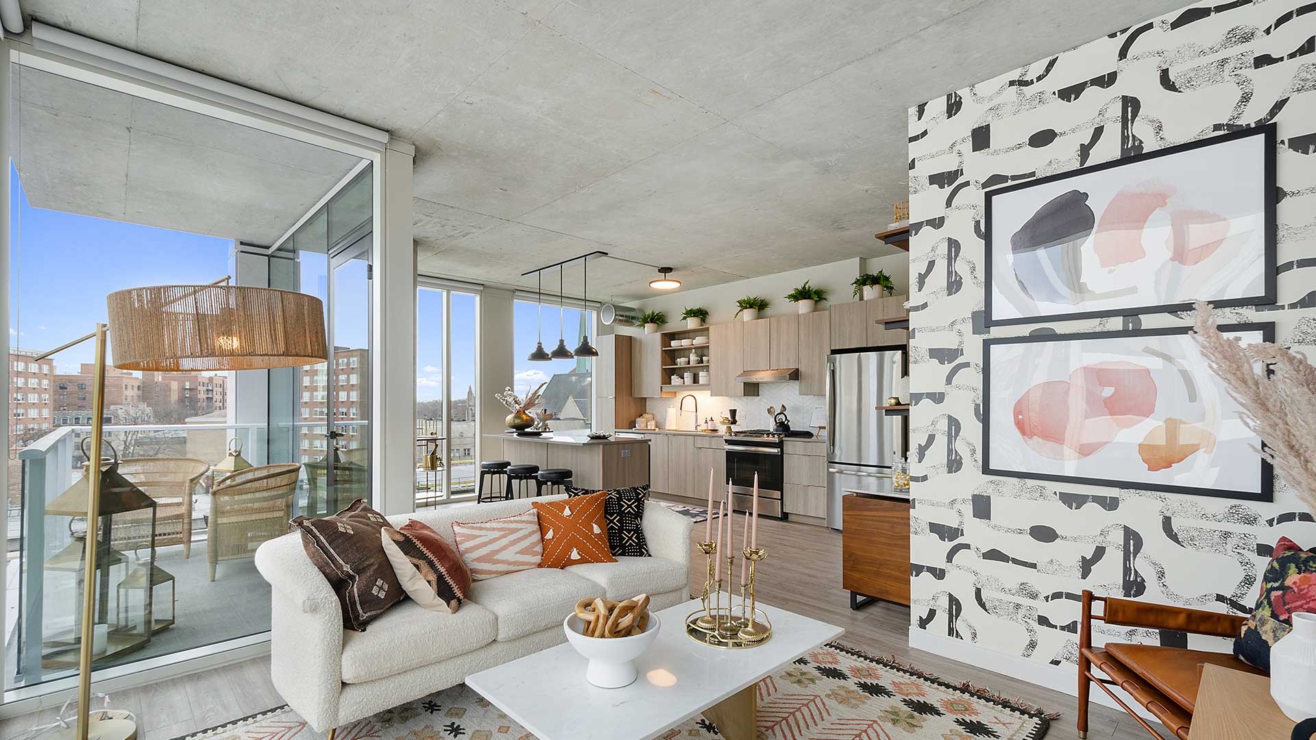 Open-concept apartment living room and kitchen with floor-to-ceiling windows, modern finishes, and access to a private balcony.