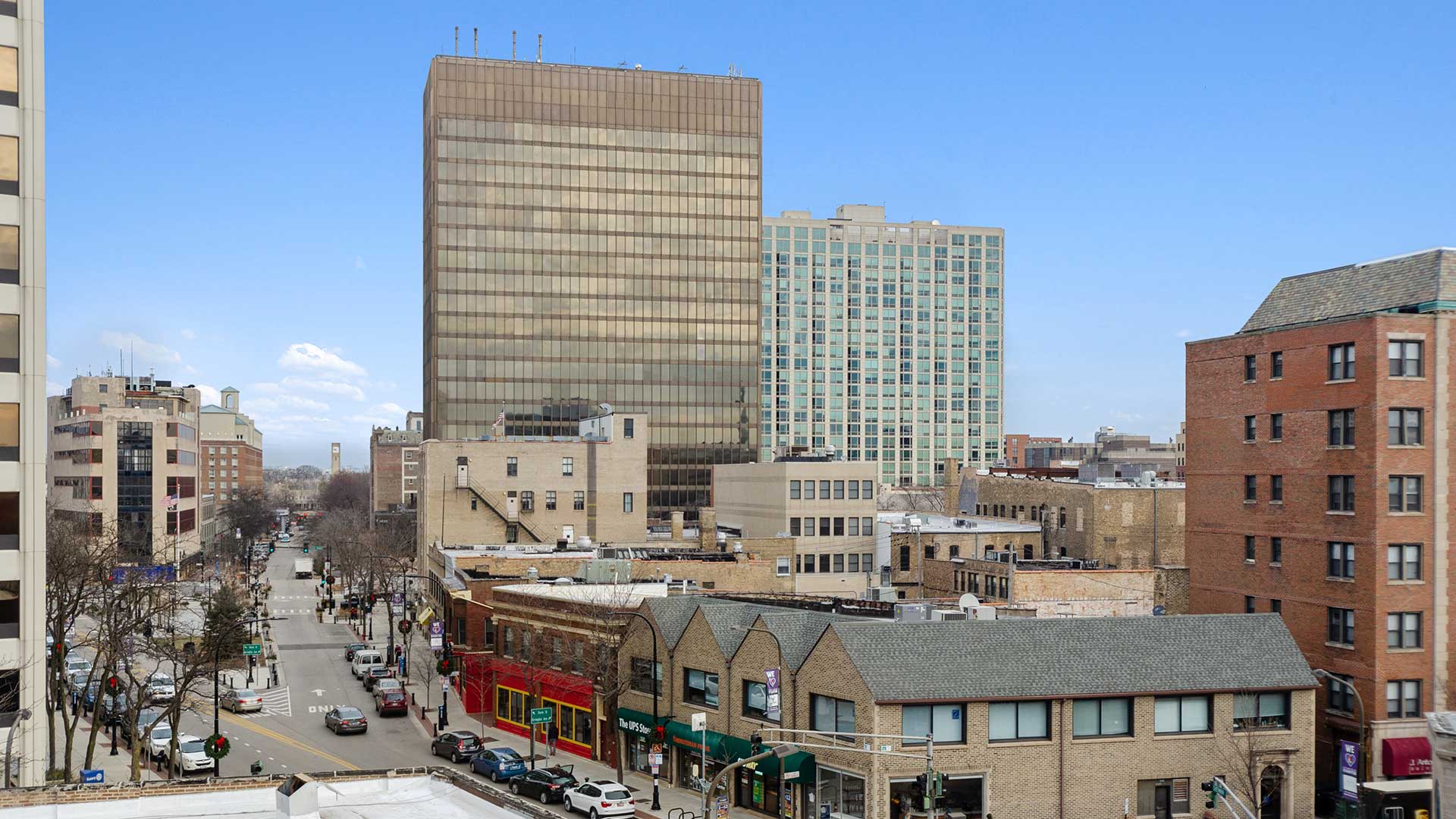 Elevated neighborhood view from an apartment overlooking city streets, shops and surrounding buildings.